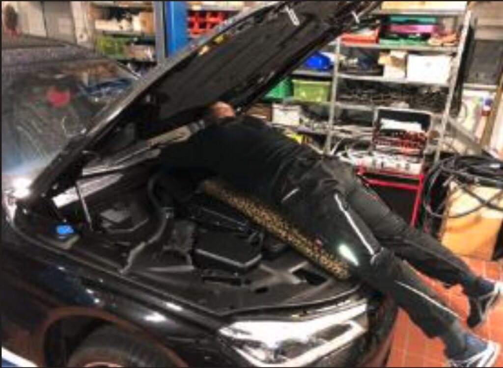 Mann gebeugt über Motorraum